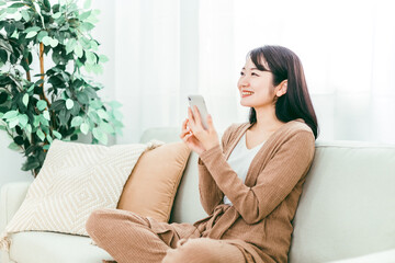 家でスマホを使う日本人女性（笑顔）
