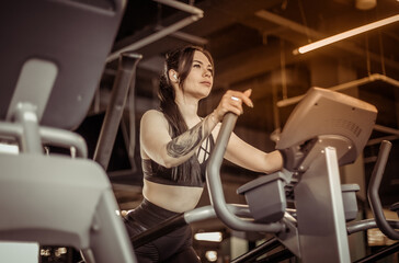 Fototapeta na wymiar Young fitness woman doing cardo workout in exercise machine at the gym. Healthy lifestyle, sport concept