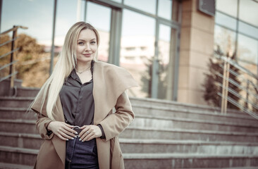 Stylish business woman in a trench coat descends the stairs