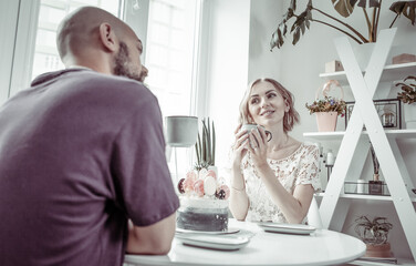 Cute couple are drinking coffee or tea in the kitchen. Husband and wife spend time together.