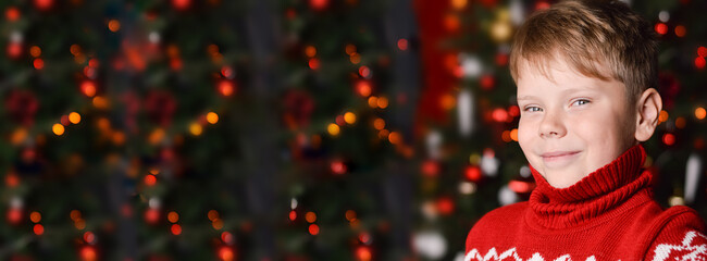 happy smiling caucasian boy in santa tee shirt and hat holding a gift box . Black christmas banner with bokeh lights