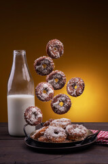 sugar-coated doughnuts falling on a plate