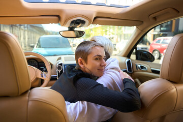 Blonde and brunette, LGBT couple, hugging in the car