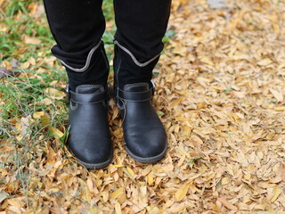 walking in autumn park boots over yellow leaves