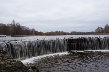 A small man-made waterfall on the lake. Lined with stones, the water froze in flight. Landscape.