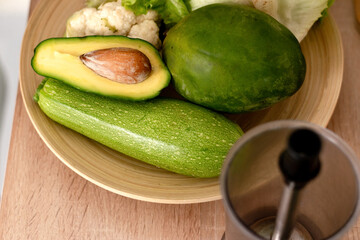 Avacado,cauliflower,mango,zucchini on a plate and blender bowl on the kitchen table.Top view,selective fosus.Healthy eating and healthy lifestyle.Cooking at home.Veganuary,vegetarian and vegan diet.