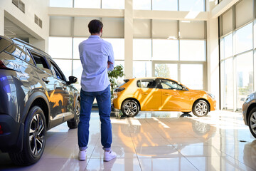 Potential buyer choosing vehicle in auto showroom - obrazy, fototapety, plakaty