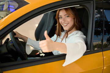 Joyous woman approving her new automobile before camera
