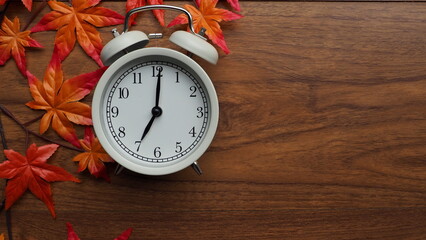 White alarm clock placed on vintage wooden floor, top view, with copy space.