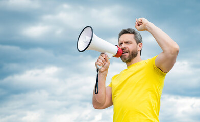 man in yellow shirt proclaim in loudspeaker on sky background