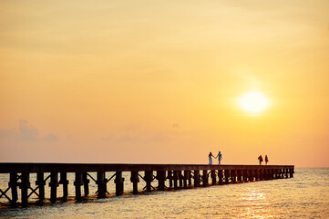 Obraz premium Pier on the sea shore at sunset time.