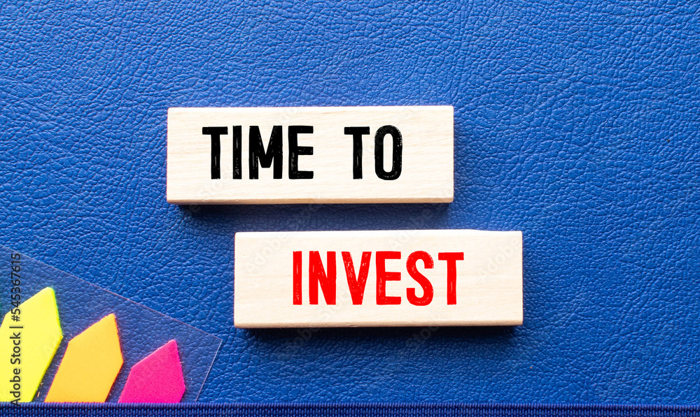 Poster a notebook with the text time for invest is leaning against the wall along with a folder with financ