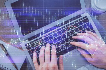 Double exposure of man's hands typing over computer keyboard and forex graph hologram drawing. Top view. Financial markets concept.