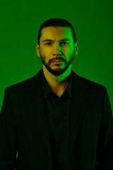 Studio portrait of bearded man wearing suit on green background.