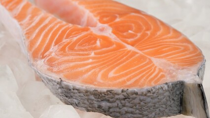 Raw, fresh salmon steak on ice cubes, rotation. Cooking salmon, seafood. Healthy food concept