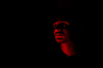 Portrait of a young man in red color light ,loneliness concept, isolated background.
