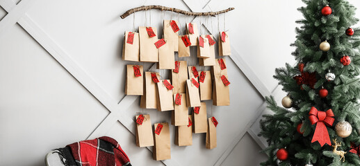 Fototapeta na wymiar Christmas tree and creative advent calendar hanging on light wall at home