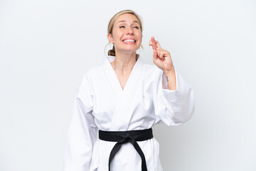 Young caucasian woman doing karate isolated on white background with fingers crossing and wishing...