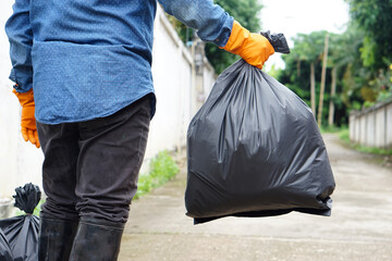 Closeup man holds black plastic bag that contains garbage inside. Concept : Waste management. Environment problems. Daily chores. Throw away rubbish.