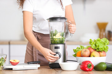 Young woman making healthy smoothie in kitchen