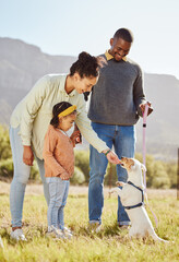Happy family with a dog in nature to relax in summer holidays or vacation walking or playing with a cute pet. Mother, father and girl child enjoy bonding or dog training a jack russell puppy animal