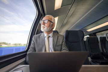 Businessman with laptop looking through window while traveling on subway or train.