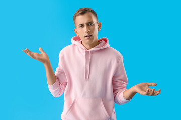 Confused young man on blue background