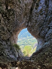 Scenic view to amazing cave in Slovenia at summer. View to green hills and forest. Natural backgrounds. Window in the rocks