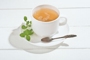 herbal tea with mint on a white wooden table. alternative medicine for gastrointestinal system...