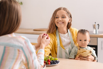 Happy lesbian couple with their little baby in kitchen