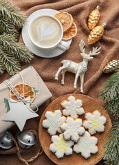 A cup of coffee latte, homemade cookies and Christmas balls and knitted sweater.