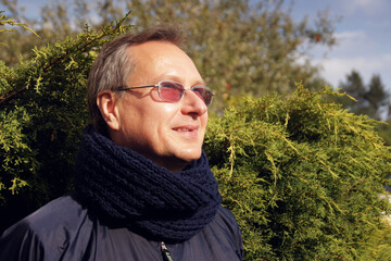 Cheerful man in a dark blue knitted scarf stands on the street