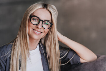 Close up portrait of gorgeous blonde Swedish woman in glasses, grey shirt with long loose hair...