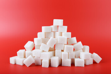 heap of white sugar cubes isolated on red background