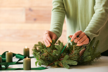 Woman making Christmas wreath at table, closeup