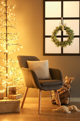 Interior of living room with Christmas mistletoe wreath, armchair and glowing lights