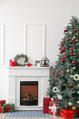 Fireplace with decor and Christmas tree near light wall