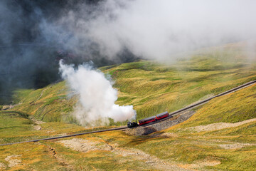 The red tourist vintage steam train ascending to the Brienzer Rothorn summit with the autumn fog
