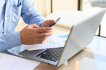 Businessman checking smartphone and laptop