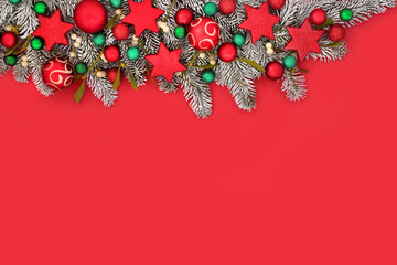 Christmas fir snow mistletoe and bauble background border. Traditional nature composition with tree decorations for festive Xmas holiday season on red.
