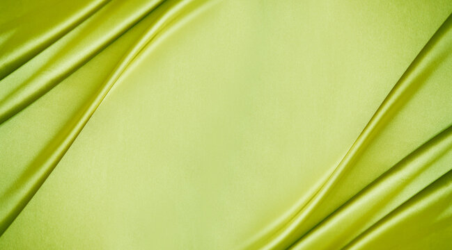 Yellow green silk satin. Lime color shiny silky smooth fabric. Soft wavy folds. Elegant background with space for design. Bright. Light. Banner. Flat lay, top view table. Template.