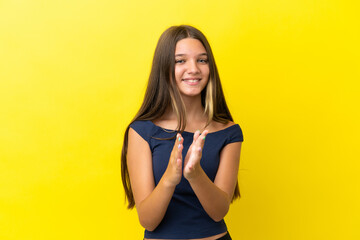 Little caucasian girl isolated on yellow background applauding after presentation in a conference
