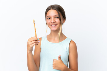Little caucasian girl holding a toothbrush isolated on white background with thumbs up because something good has happened