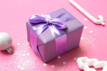 Composition with Christmas gift, decorations and sequins on pink background