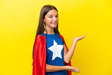 Little caucasian superhero girl isolated on yellow background extending hands to the side for inviting to come