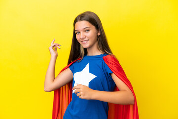 Little caucasian superhero girl isolated on yellow background making guitar gesture