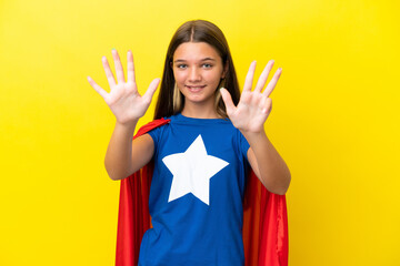 Little caucasian superhero girl isolated on yellow background counting nine with fingers