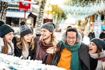 Happy friends group walking at european city on winter day - Xmas holidays life style concept with young people having fun together outdoors under Christmas snow decorations - Bright vivid filtyer