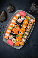 Assorted Japanese sushi rolls set with salmon, tuna, shrimp, eel, avocado, cream cheese, cucumber on a plate.