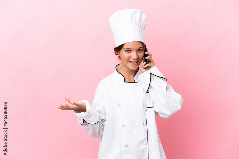 Sticker Little caucasian chef girl isolated on pink background keeping a conversation with the mobile phone with someone